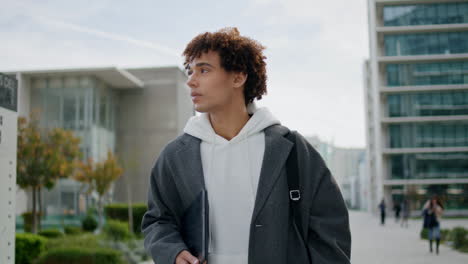 Relaxed-student-walking-city-alone-close-up.-Curly-freelancer-carrying-tablet