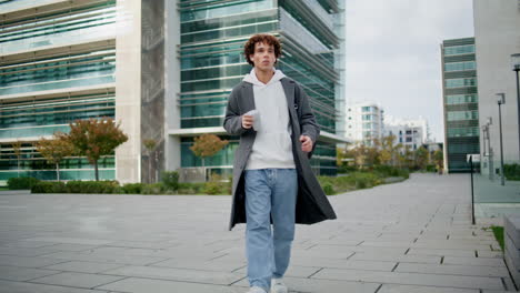 Relaxed-student-walking-downtown-alone.-Trendy-guy-enjoying-espresso-in-street