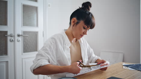 Thoughtful-creator-working-scissors-home-closeup.-Tattoo-artist-cutting-sketches