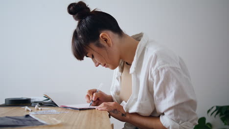 Artista-Positivo-Dibujando-Un-Cuaderno-En-El-Primer-Plano-Del-Lugar-De-Trabajo-Remoto.-Dibujo-Mujer