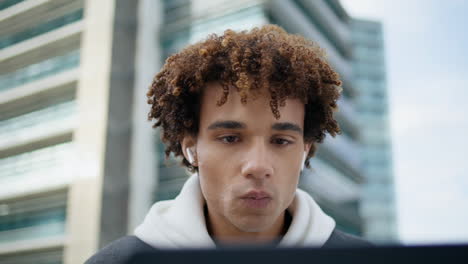 Earbuds-hipster-sipping-coffee-at-urban-place-closeup.-Student-learning-laptop