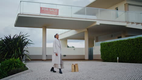 Realtor-posing-sale-house-in-cloudy-day.-Stylish-african-woman-hunting-property