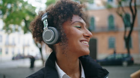 Chica-Positiva-Escuchando-Una-Canción-Con-Auriculares-En-El-Primer-Plano-De-La-Calle.-Señora-Disfrutando-De-La-Música