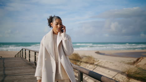 Stressed-businesswoman-talking-smartphone-on-beach-weekend.-Serious-woman-walk