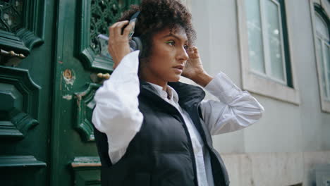 Woman-wearing-wireless-headphones-at-street-close-up.-Girl-in-headset-vertical