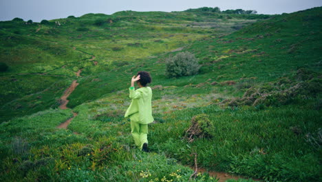 Stylish-woman-performer-dancing-walking-on-green-field-cloudy-evening-vertically