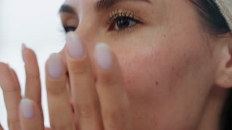 Woman-face-moisturizing-at-bath-room-closeup.-Lady-applying-facial-foundation