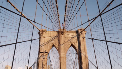 Walking-Through-Mesh-Cables-and-Arches-of-Brooklyn-bridge-on-Sunny-Day,-Tilt-Up,-Dolly,-Forward