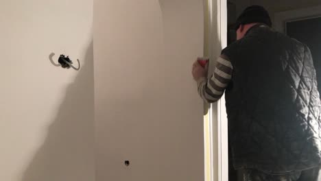 Fifty-seven-year-old-man-sanding-new-white-wall-with-float-sander-in-4k