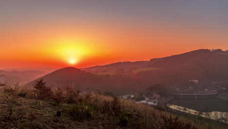 Sonnenuntergang-Im-Zeitraffer,-Wenn-Die-Sonne-Hinter-Hügeln-Und-Bergen-Voller-Bäume-Und-Sich-Bewegender-Wolken-Steht,-Hinter-Denen-Die-Sonne-Einen-Kräftig-Gelb-orangefarbenen-Blick-Auf-Die-Umliegende-Natur-Der-Beskydy-Berge-Untergeht