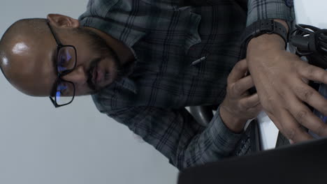 Close-up-vertical-video-of-a-young-male-Indian-entrepreneur-working-in-his-startup-office-inputting-financial-figures-into-his-business-proposal