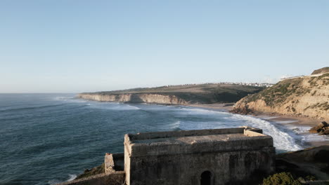Reveal-drone-shot-in-front-of-a-ruin-at-Ericeira-beach
