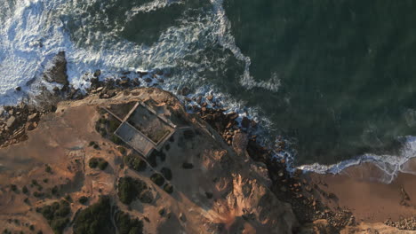 Top-down-drone-shot-of-the-ruin-at-Ericeira-flying-at-to-the-ocean