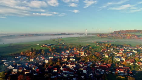 Aerial-backwards-shot-of-small-village-and-castle-in-Germany-during-sunset-in-autumn