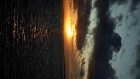 Vertical-handheld-shot-of-a-stunning-golden-sunset-from-the-Barra-Lighthouse-lookout-in-Salvador-the-state-of-Bahia,-Brazil-looking-out-at-the-water-in-the-Bay-of-All-Saints-on-a-warm-fall-evening