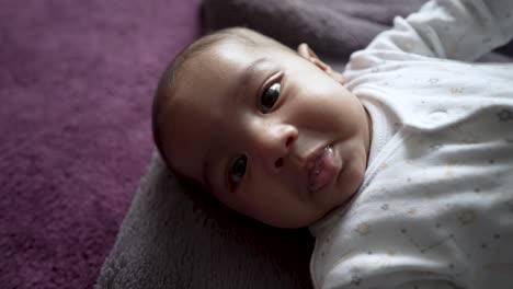 Adorable-2-Month-Old-Indian-Baby-Boy-Looking-Wide-Eyed-At-Camera-Wriggling-Whilst-Laying-On-Blanket-On-The-Floor