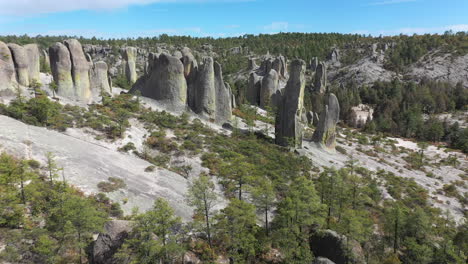 Travelers-standing-on-rock-formations-of-Valle-de-los-Monjes,-Chihuahua,-forward-aerial