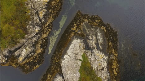 Große-Klippen-Im-Wasser,-Bedeckt-Mit-Gras,-Drohnenansicht-Von-Oben-Nach-Unten