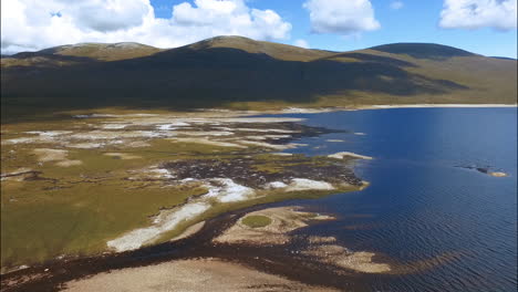 Swampy-Coastline-in-Scotland-with-Highlands-in-Background,-Aerial-Dolly-in