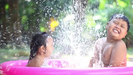 Two-Asian-children-are-playing-water-in-the-pool-with-full-of-happiness