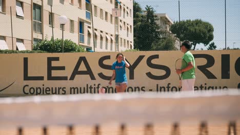 El-Entrenador-De-Tenis-Observa-A-Un-Estudiante-Haciendo-Un-Servicio-Y-Chocando-Los-Cinco-Entre-Sí