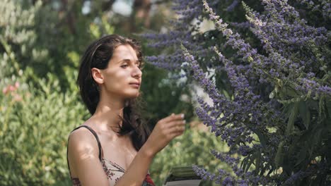 La-Mujer-Sonriente-Huele-El-Aroma-De-Las-Flores-Lilas-Moradas-En-Los-Jardines-Botánicos-Del-Museo-De-La-Perfumería