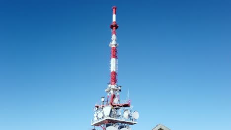 Telecommunication-tower-with-many-discs-around-on-top-of-an-Austrian-House-in-Pfaender-Austria