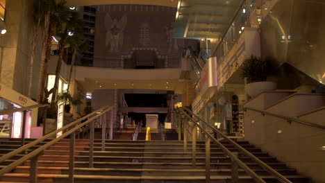 POV-shot-while-people-passing-by-while-going-up-stairs-in-Hollywood-and-Highland-Center,-Los-Angeles,-USA-at-night-time