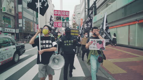 Hong-Kong-Protesta-En-Solidaridad-Con-Los-Manifestantes-Que-Marchan-Con-Pancartas,-Banderas,-Megáfonos-Y-Pancartas-Escoltados-Por-Un-Policía-En-Tokio,-Japón