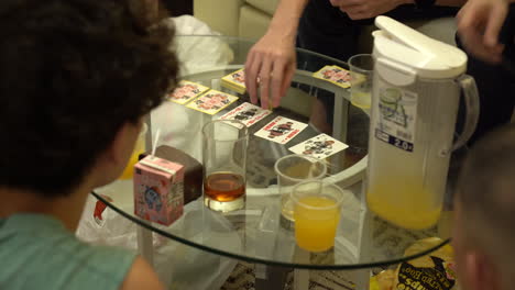 Freunde-Essen-Chips,-Trinken-Saft-Und-Spielen-Karten-In-Hongkong-über-Einem-Glastisch