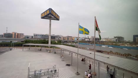 The-IKEA-store-is-located-next-to-a-road-where-many-cars-are-travelling,-and-the-flags-of-Sweden-and-India-are-flying