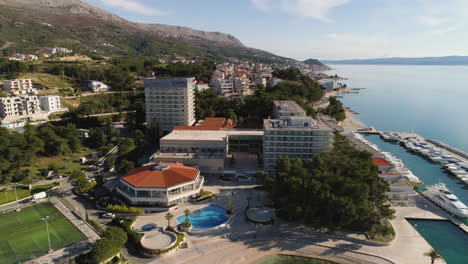 Majestic-resort-hotel-in-Split-city-area-with-luxury-yachts-moored-at-pier,-aerial-fly-over-shot