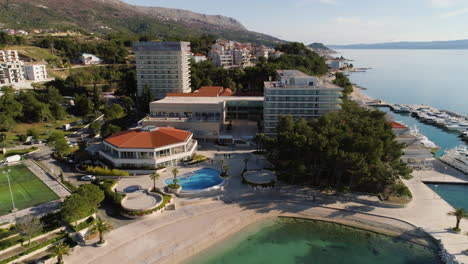 Edificio-De-Hotel-Costero-Con-Campo-De-Fútbol-Y-Yates-De-Lujo-En-Croacia,-Ciudad-Dividida,-Vista-Aérea-De-Drones