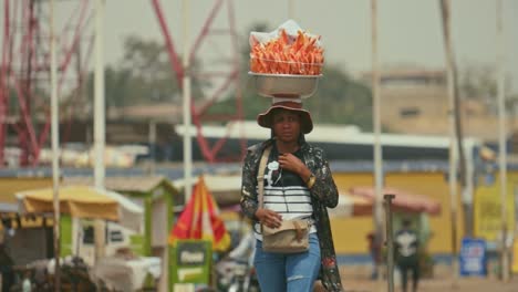 Vendedora-De-Comida-Callejera-Africana-Caminando-En-Cámara-Lenta-Con-Un-Paquete-En-La-Cabeza---Togo,-áfrica