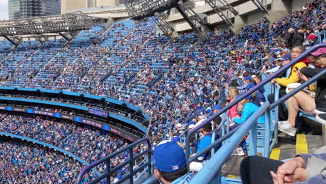 Simpatizantes-En-Los-Puestos-Del-Estadio-Apoyando-Al-Equipo-Del-Club-De-Béisbol-Blue-Jays-De-Toronto,-Multitud-De-Espectadores-Viendo-El-Partido-Durante-El-Evento-Deportivo,-Con-Asientos-En-Las-Gradas,-Ola-Del-Estadio