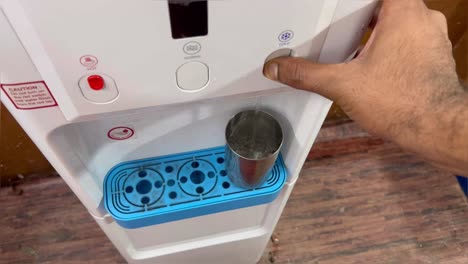 Una-Foto-De-ángel-Superior-De-Un-Hombre-Llenando-Un-Vaso-De-Acero-Con-Agua-De-Un-Purificador-De-Agua-En-Casa