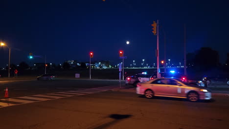 Policías-Y-Coches-De-Policía-Estacionados-En-La-Carretera-Por-La-Noche-Con-Tráfico-Urbano