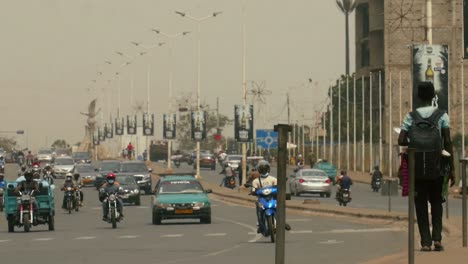 Street-vendor-walking-on-the-sidewalk-with-incoming-traffic---Togo,-Africa