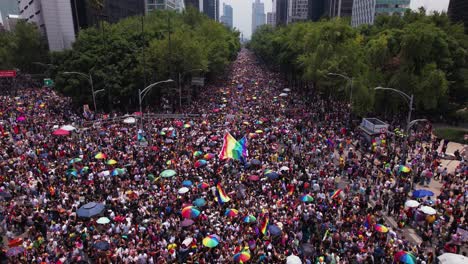 Vista-Aérea-De-Personas-Ondeando-Una-Bandera-Arcoíris-En-La-Marcha-Del-Orgullo-Gay-En-La-Soleada-Ciudad-De-México---Reversa,-Disparo-De-Drones