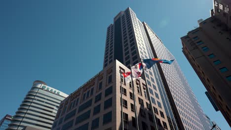 Bandera-De-Asean,-Singapur-Y-República-De-Corea-Que-Se-Eleva-Sobre-Astas-De-Bandera-Cerca-De-Sfc---Edificio-Del-Centro-Financiero-De-Seúl-Contra-El-Cielo-Azul