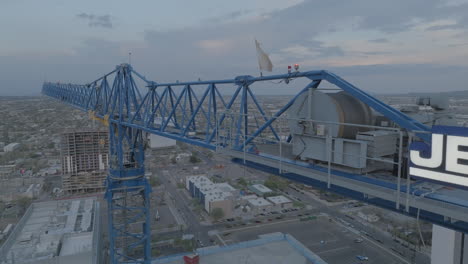 Drone-shot-of-a-construction-crane-over-the-city-at-twilight,-aerial-shot