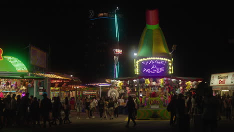 Las-Luces-De-Neón-Brillan-Mientras-La-Gente-Juega-Juegos-De-Carnaval-En-Una-Noche-Ocupada-En-El-Cne