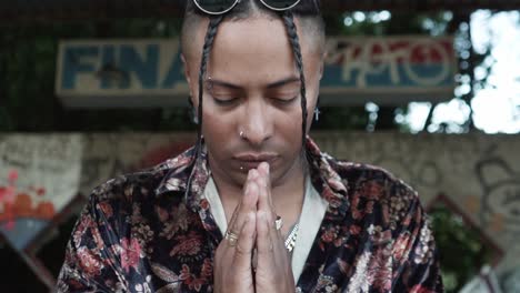 Hispanic-man-praying-in-front-of-an-abandoned-building