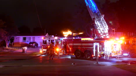 Fire-engine-truck-extending-tall-ladder-over-flaming-house-during-dark-night