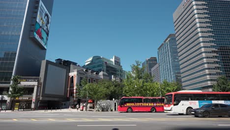 Car-traffic-at-Sejong-daero-street-and-Red-Seoul-city-tour-bus-parked-waiting-for-tourists-at-downtown---establishing-shot