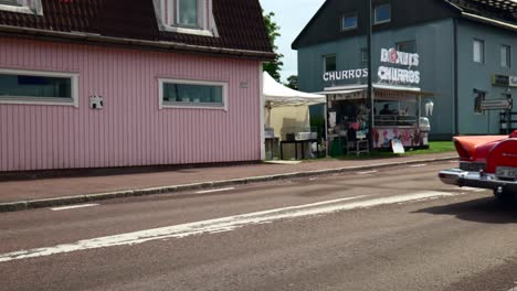 Red-Vintage-Convertible-Car-Driving-Through-Small-Town-in-Northern-Sweden