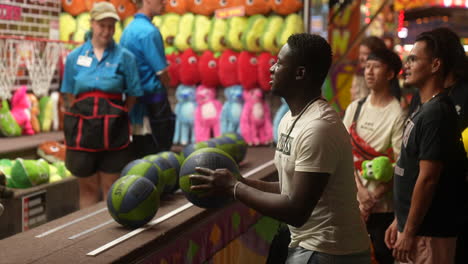 A-crowd-claps-and-cheers-as-a-man-tries-to-win-a-prize-by-playing-a-basketball-carnival-game