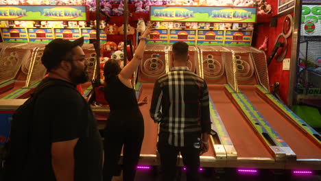 Una-Pareja-Juega-Un-Juego-De-Arcade-De-Skee-ball-Durante-Una-Divertida-Velada-En-Un-Carnaval