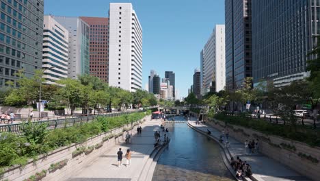 La-Gente-Viaja-En-El-Centro-De-La-Ciudad-De-Seúl-Caminando-A-Lo-Largo-Del-Arroyo-Cheonggye-En-Un-Día-Soleado-Y-Despejado