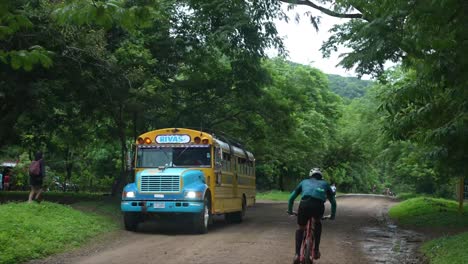 Ciclista-De-Carretera,-Autobús-Estudiantil-Pasando-Sobre-El-Río,-Pueblo-Pobre,-Calles-Rivas,-Nicaragua,-Pueblo-Colonial,-Casas-Pobres,-Nicaragüense,-Mtb